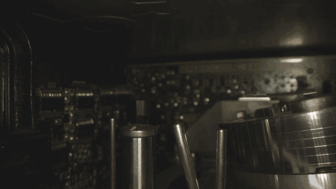 Produktfilm Probe Lens Berlin Gif Nahaufnahme eines Drehmechanismus in einem alten VHS-Videorecorder. Das Bild zeigt Metallkomponenten und elektronische Schaltkreise in Sepiatönen, wodurch die komplizierten Details und mechanischen Teile des Geräts hervorgehoben werden.